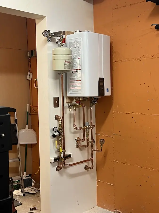 Plumbing technician inspecting water heater connections in Skaneateles